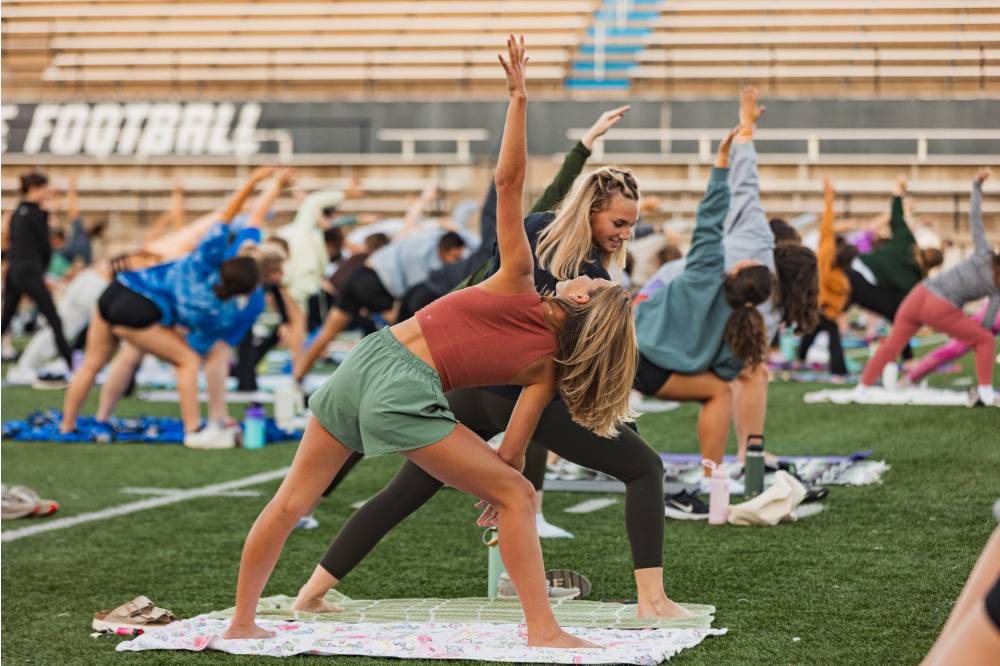 students doing various yoga poses on the football field